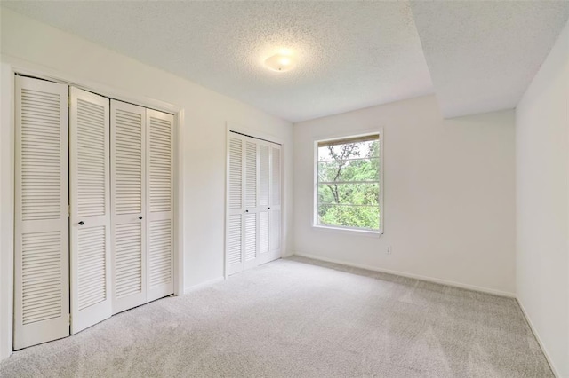 8277 Kingsbrook Rd Unit 254, Houston, TX 77024 - unfurnished bedroom featuring a textured ceiling, multiple closets, carpet flooring, and baseboards