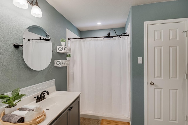 bathroom featuring a textured wall, vanity, a shower with curtain, and backsplash