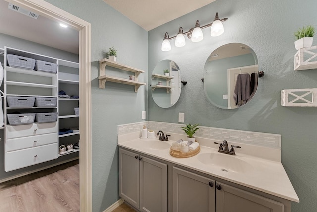 full bathroom featuring double vanity, wood finished floors, visible vents, and a sink