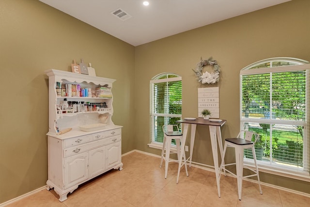 interior space featuring baseboards, visible vents, light tile patterned floors, and a wealth of natural light