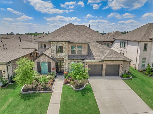 view of front of home with a shingled roof, brick siding, a garage, a front yard, and concrete driveway