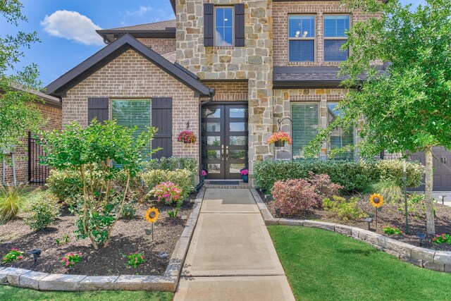 entrance to property with french doors, stone siding, a shingled roof, and brick siding