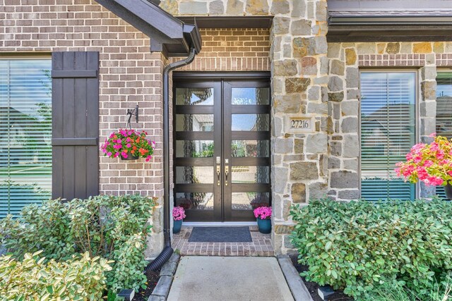doorway to property with brick siding, french doors, and stone siding