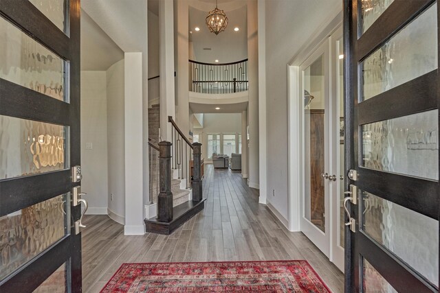 foyer with baseboards, wood finished floors, stairway, and a towering ceiling