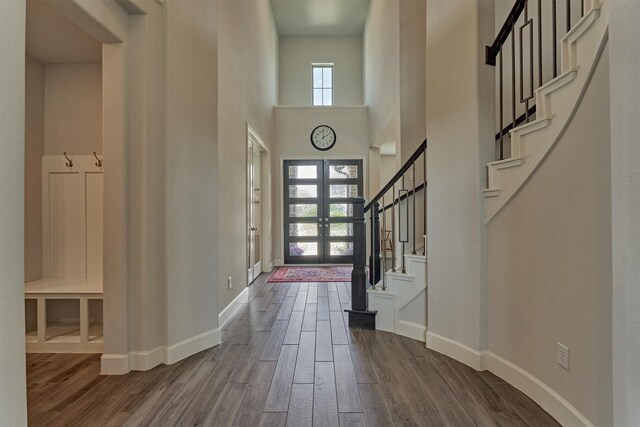 foyer with stairs, baseboards, dark wood finished floors, and a towering ceiling