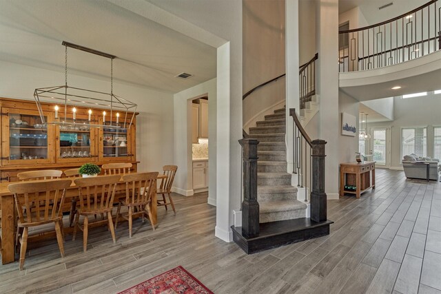 dining space with baseboards, wood finished floors, visible vents, and stairway