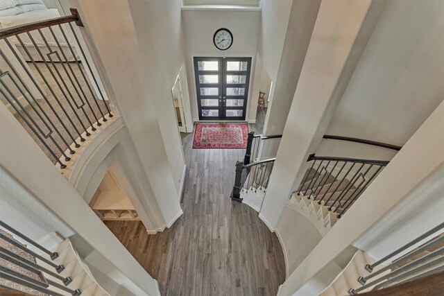 staircase with wood finished floors, a high ceiling, and french doors