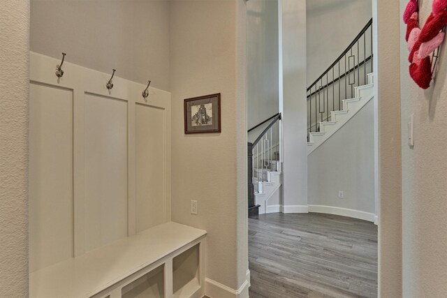 mudroom featuring baseboards, a high ceiling, and wood finished floors