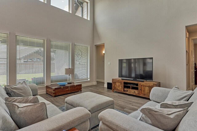 living area with wood finished floors, baseboards, and a high ceiling