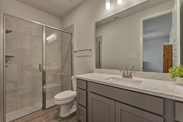 bathroom featuring vanity, toilet, visible vents, and a stall shower