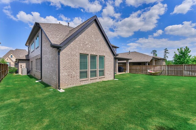 back of property with brick siding, a fenced backyard, a lawn, and cooling unit