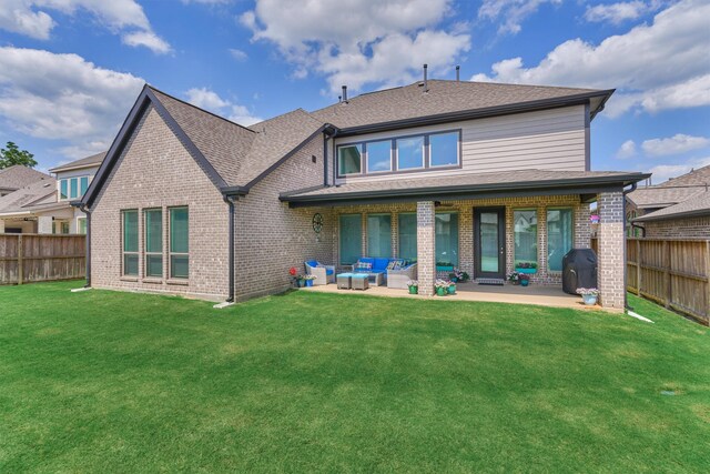 rear view of property with brick siding, a fenced backyard, a lawn, and a patio