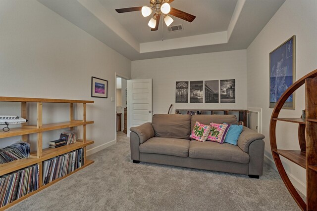 carpeted living area with baseboards, ceiling fan, visible vents, and a tray ceiling