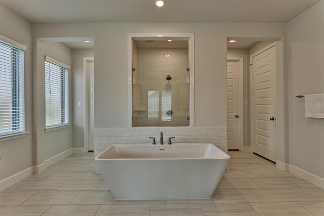 bathroom with a freestanding bath, baseboards, a tile shower, and recessed lighting