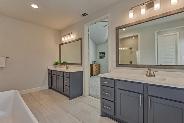 full bath with visible vents, tiled shower, a freestanding bath, two vanities, and a sink