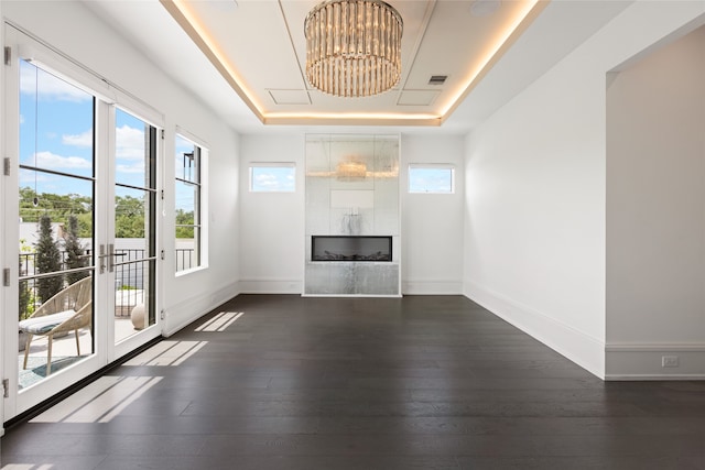 unfurnished living room featuring visible vents, dark wood-type flooring, a raised ceiling, and a fireplace
