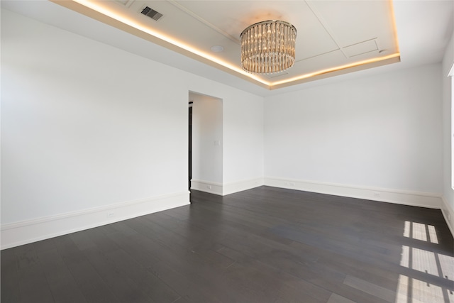 unfurnished room with a raised ceiling, baseboards, dark wood finished floors, and visible vents