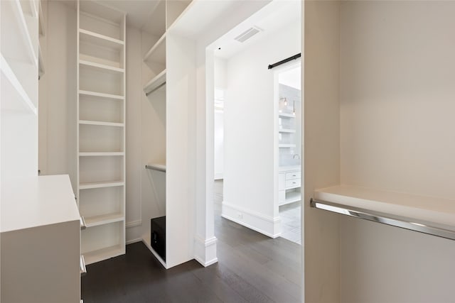 walk in closet with visible vents and dark wood finished floors