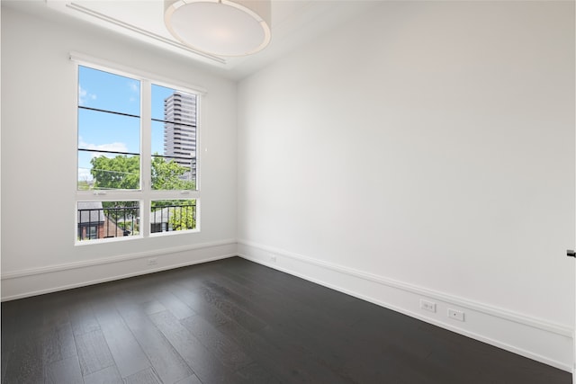 spare room featuring baseboards and dark wood-style floors