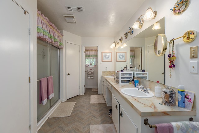full bath featuring a sink, double vanity, visible vents, and a shower stall