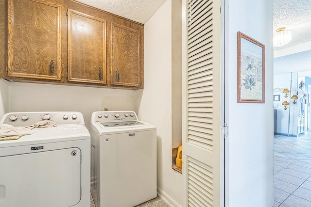 washroom with cabinet space, light tile patterned floors, washing machine and dryer, baseboards, and a textured ceiling