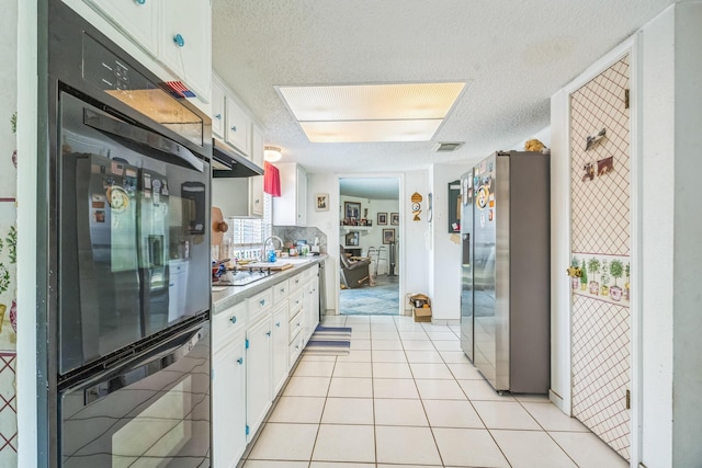 kitchen featuring a textured ceiling, white cabinets, stovetop, light countertops, and stainless steel fridge