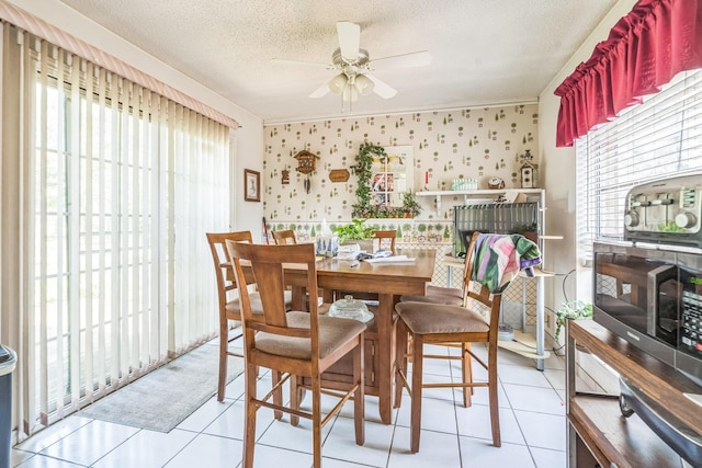 dining space featuring wallpapered walls, a ceiling fan, a wealth of natural light, and light tile patterned floors