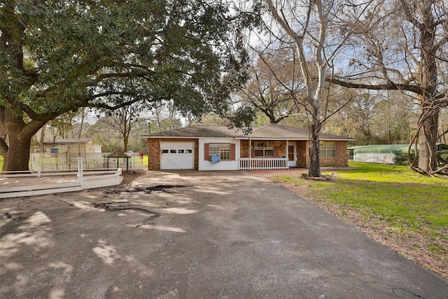 single story home with a porch, fence, aphalt driveway, a garage, and a front yard