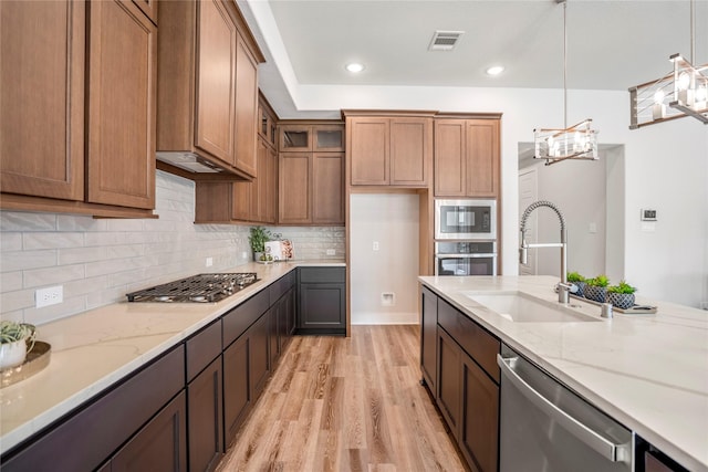 17335 Sunflower Petals Trl, Conroe, TX 77302 - kitchen featuring light stone countertops, stainless steel appliances, light wood-type flooring, and a sink