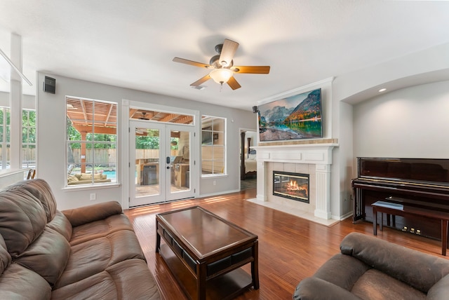 living room with a ceiling fan, french doors, wood finished floors, and a tile fireplace