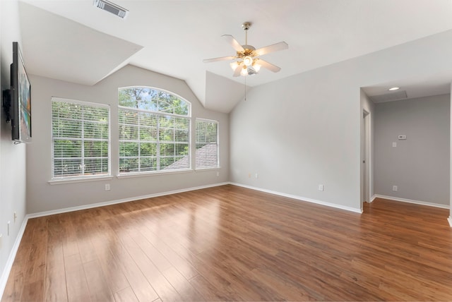 empty room with visible vents, wood finished floors, baseboards, a ceiling fan, and vaulted ceiling