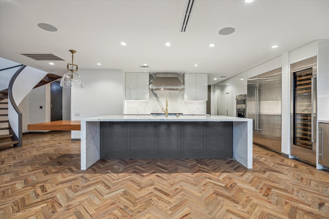 5756 Indian Cir, Houston, TX 77057 - kitchen with wall chimney range hood, appliances with stainless steel finishes, beverage cooler, light countertops, and modern cabinets