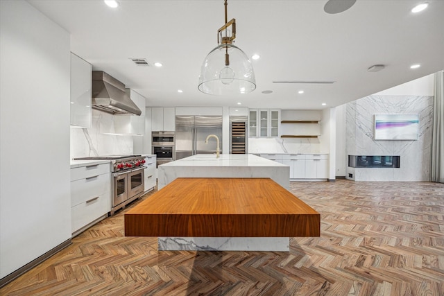 5756 Indian Cir, Houston, TX 77057 - kitchen with wall chimney range hood, white cabinets, premium appliances, beverage cooler, and modern cabinets