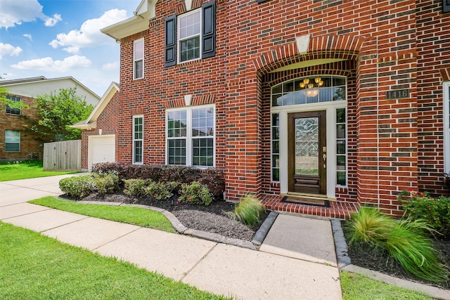 entrance to property with driveway, brick siding, and a garage