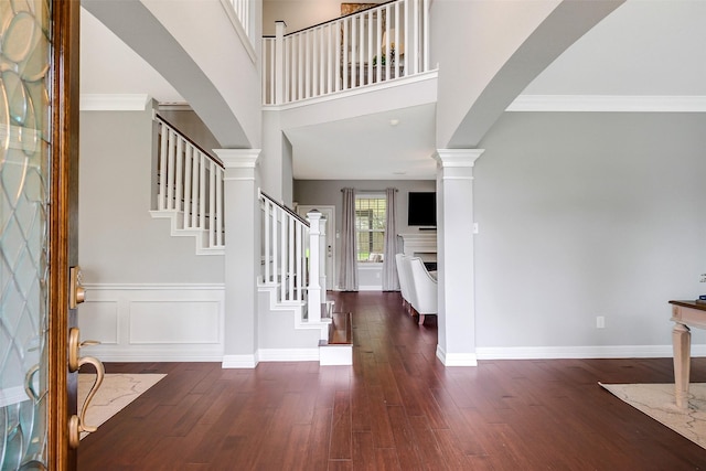 entryway with stairway, wood finished floors, and arched walkways