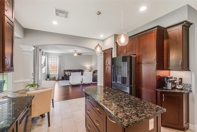 kitchen featuring arched walkways, ornate columns, freestanding refrigerator, ceiling fan, and visible vents