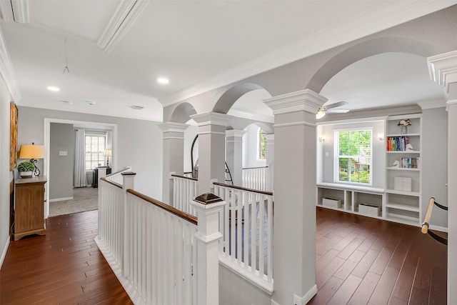 hallway featuring ornamental molding, an upstairs landing, arched walkways, and decorative columns