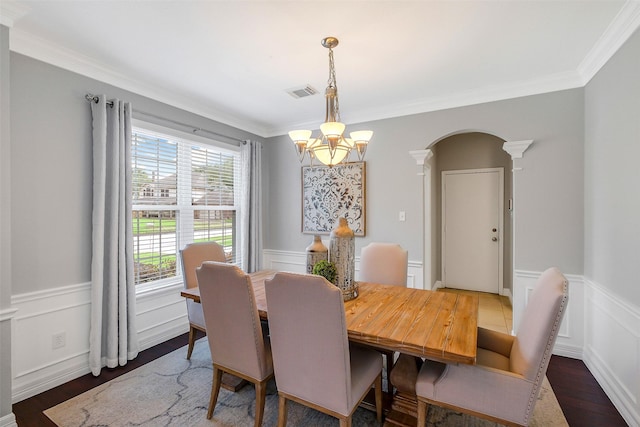 dining space with a chandelier, crown molding, visible vents, and arched walkways
