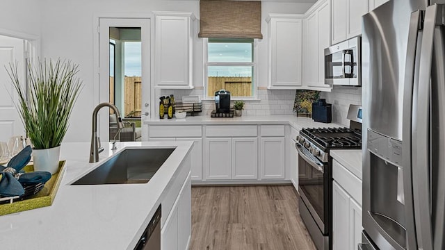7703 Basil Ridge Dr, Cypress, TX 77433 - kitchen with a sink, light wood-style floors, stainless steel appliances, white cabinetry, and backsplash