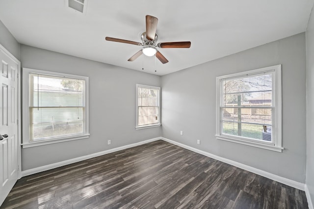 empty room featuring baseboards, ceiling fan, and dark wood finished floors