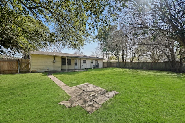 back of house with a fenced backyard and a lawn