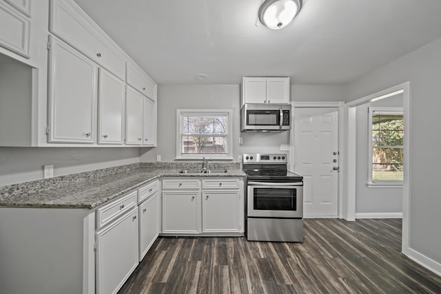 kitchen with a sink, appliances with stainless steel finishes, dark wood finished floors, and white cabinetry