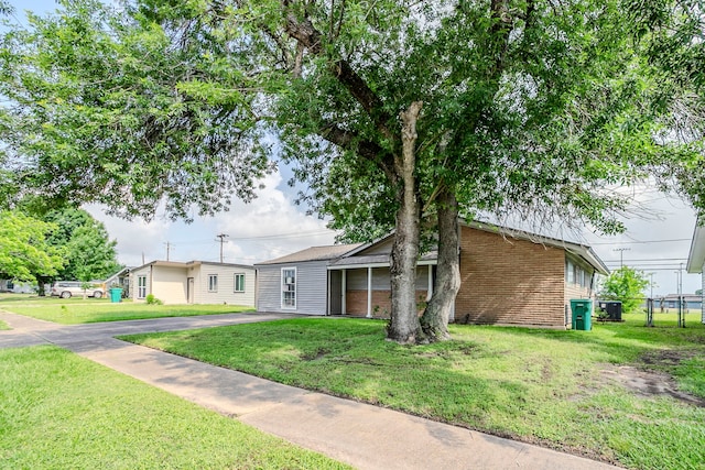 view of front of property featuring driveway, a front yard, and brick siding