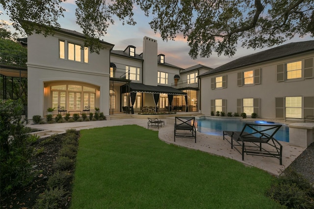 1069 Kirby Dr, Houston, TX 77019 - rear view of house with an outdoor pool, a patio area, a chimney, a lawn, and stucco siding