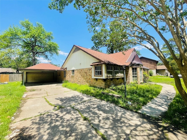 view of side of home with fence, brick siding, and a garage