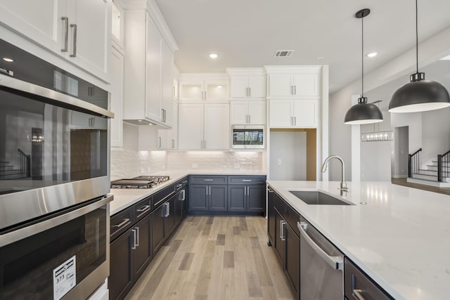 9722 Leafgate Ct, Missouri City, TX 77459 - kitchen featuring light wood finished floors, recessed lighting, a sink, stainless steel appliances, and white cabinets