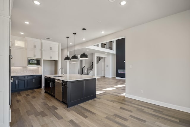 9722 Leafgate Ct, Missouri City, TX 77459 - kitchen featuring white cabinets, a sink, stainless steel appliances, light countertops, and light wood finished floors