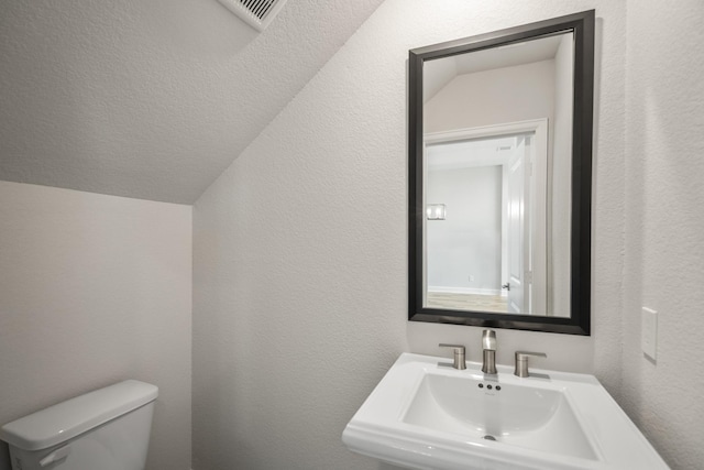 9722 Leafgate Ct, Missouri City, TX 77459 - bathroom with visible vents, toilet, a textured wall, and a sink