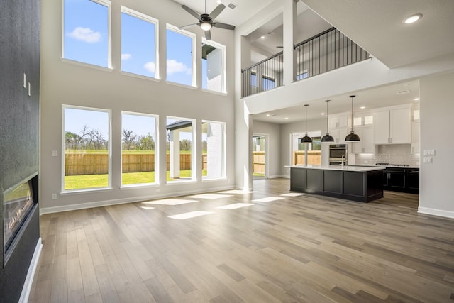 9722 Leafgate Ct, Missouri City, TX 77459 - unfurnished living room featuring light wood-type flooring, a ceiling fan, plenty of natural light, and a towering ceiling
