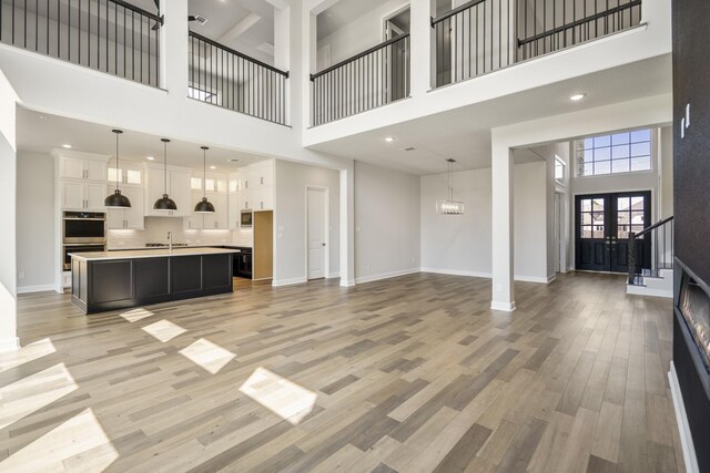 9722 Leafgate Ct, Missouri City, TX 77459 - unfurnished living room featuring recessed lighting, light wood-style flooring, a sink, baseboards, and a high ceiling